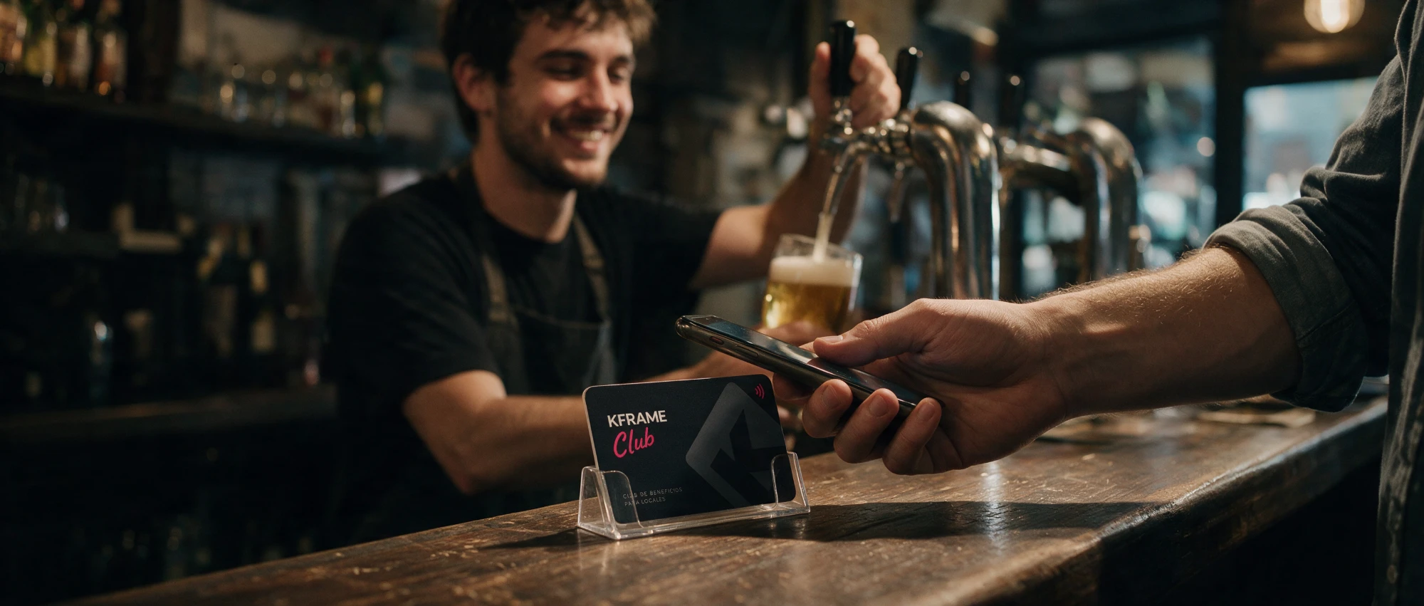 En la barra de un bar, un cliente acerca el celular a la tarjeta del club mientras el barman sirve una cerveza